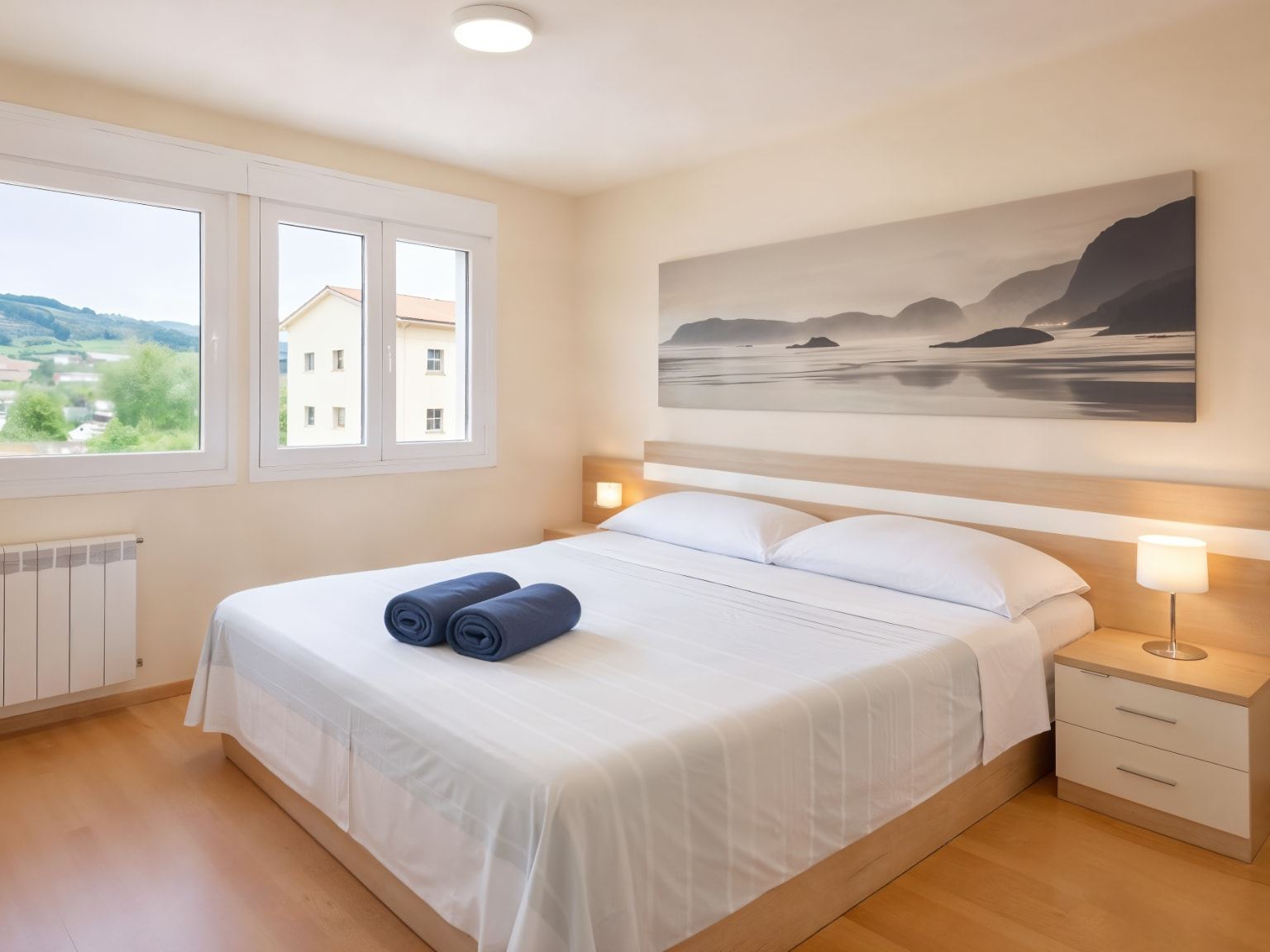Dormitorio doble luminoso de Nova MSuites Catedrales con ropa de cama blanca y un lienzo costero sobre el cabecero