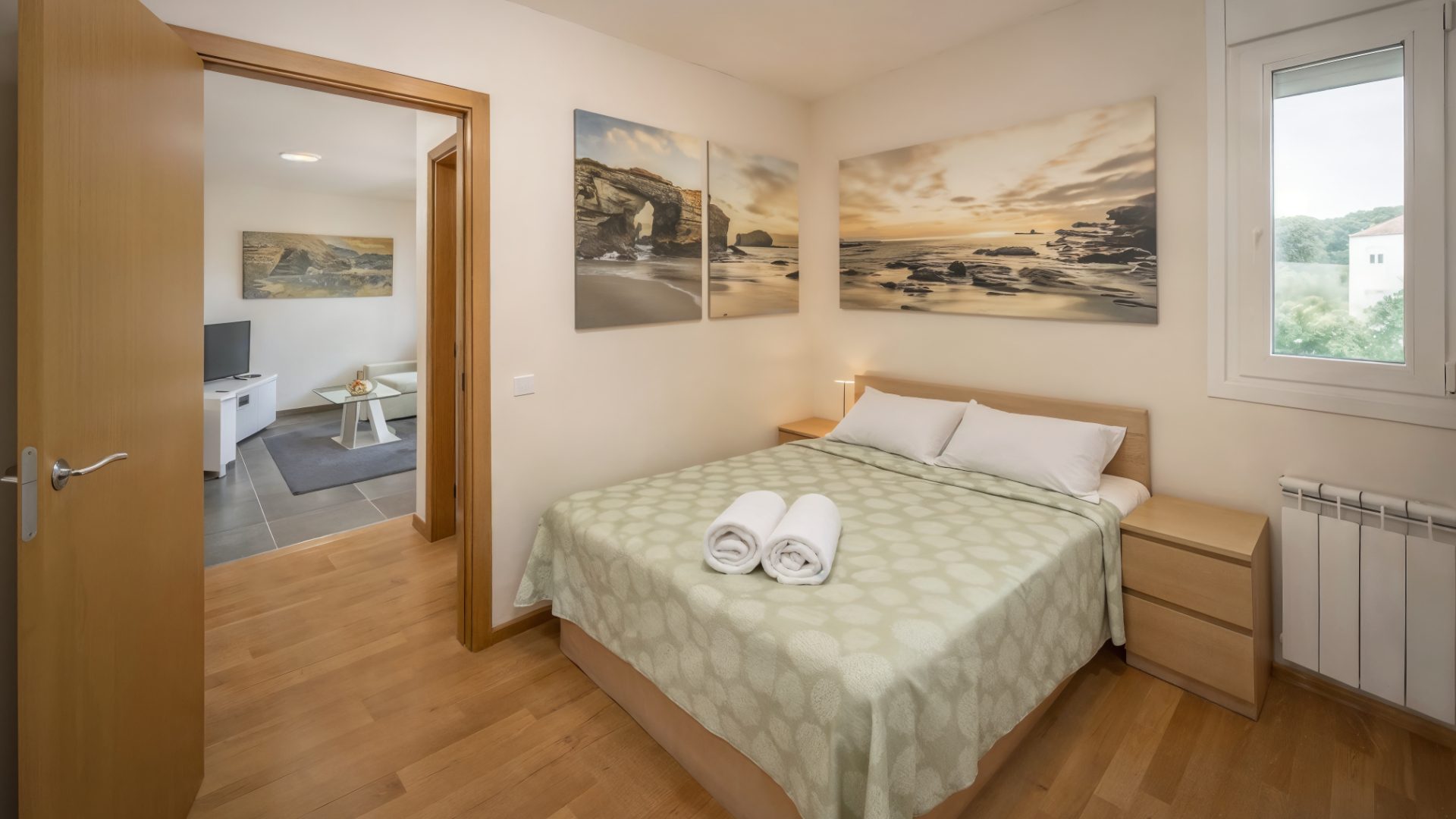 Salón del apartamento de 2 habitaciones de Nova MSuites Catedrales, con sofá rinconera crema y ventanal panorámico
