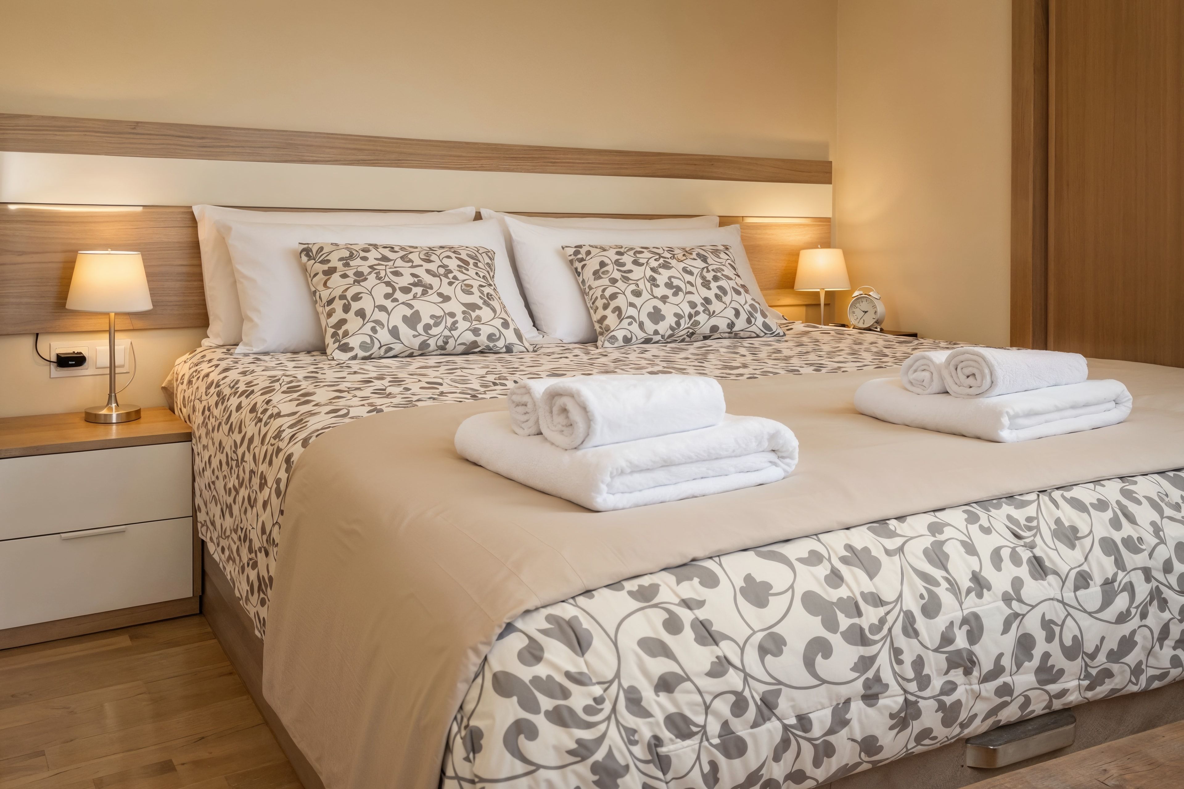 Dormitorio doble de Nova MSuites Catedrales con cama amplia, cabecero de madera y toallas enrolladas
